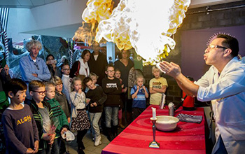 Mad scientist blowing fire out of his hands in front of children