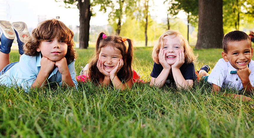 group of kids lying down on their stomachs in the Park on the grass