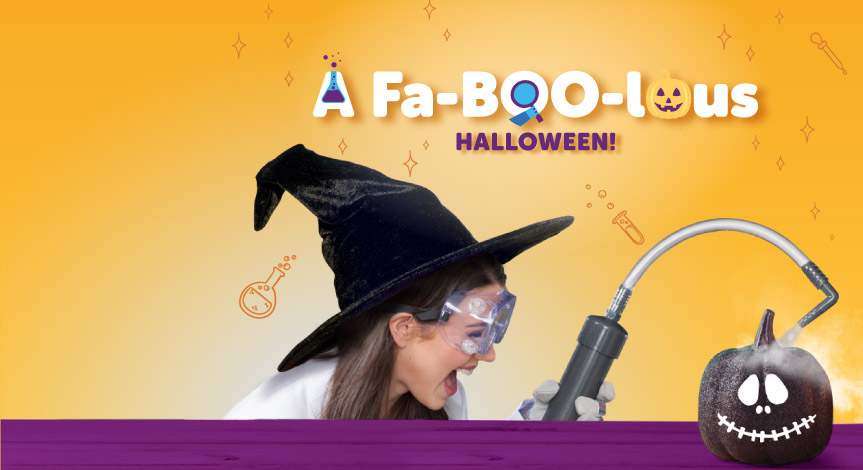 A mad science instructor wearing a witch hat using the mad science smoke shower machine over a black pumpkin.