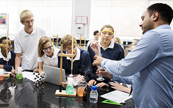 Group of high school students in a lab listening to their teacher