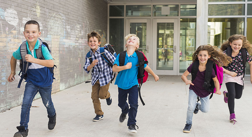 Kids wearing school bags running outside school