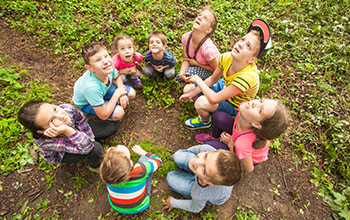 Kids sitting in a circle outside looking up at the sky