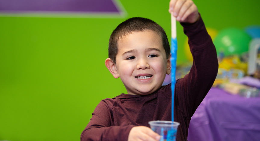 Boy playing with slime in an Activity Cup that he made at a birthday party.